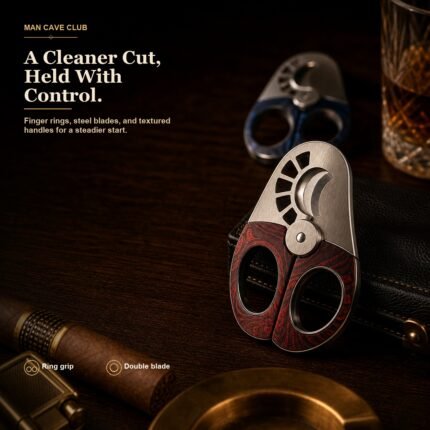 stainless steel double blade cigar cutter with textured finger-ring handle on a cigar tray